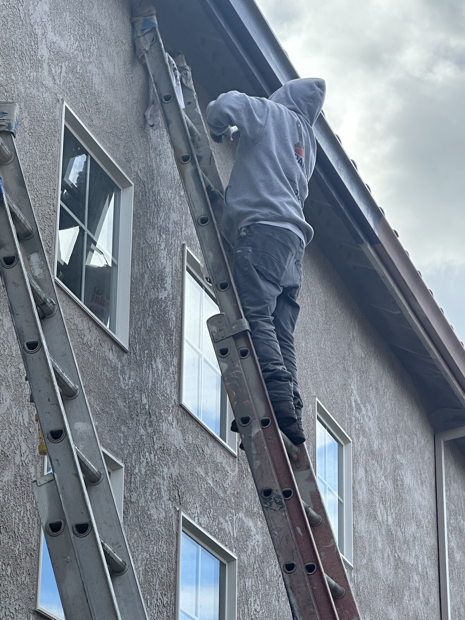 Painting By Ken crew member painting a home exterior from a ladder